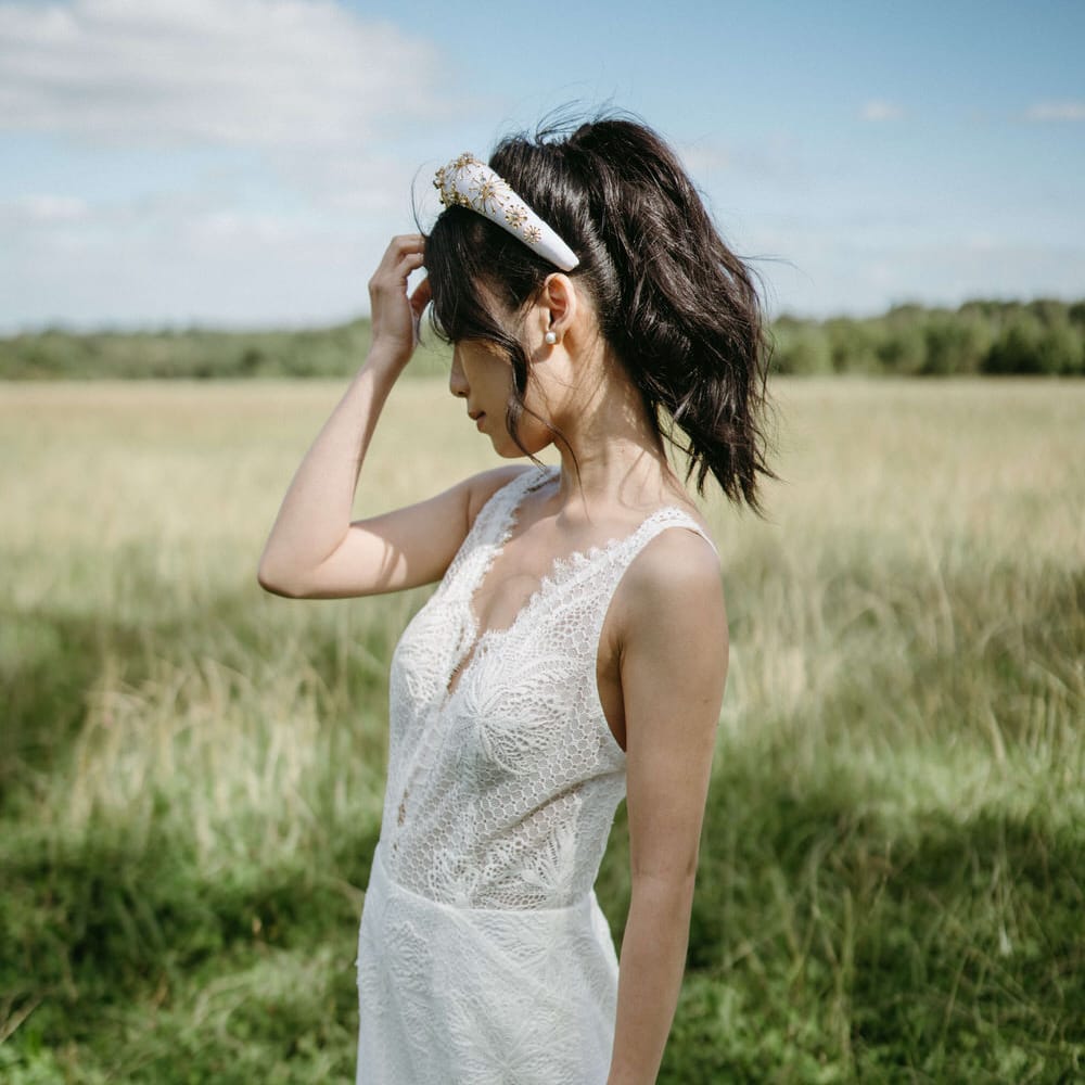 Bride wearing a lace wedding dress with plunge neckline and a white and gold beaded headband