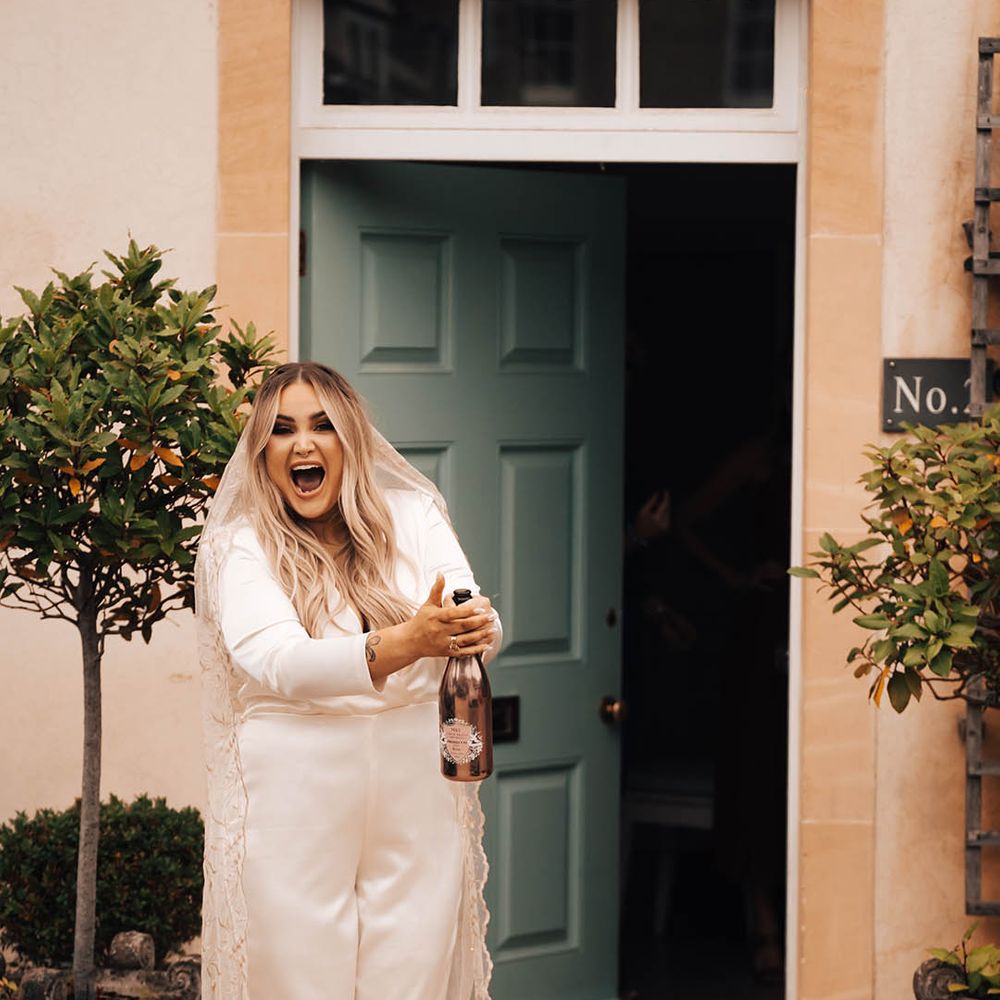 Blonde bride pops champagne outdoors on her wedding day