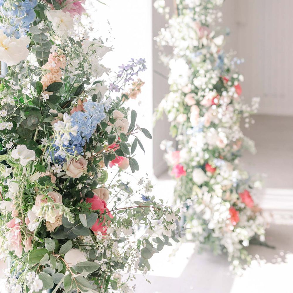 Vertical floral arrangements with pastel pink, blue, peach and white wedding flowers mixed with foliage