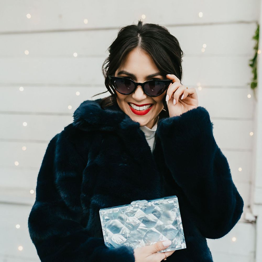 Stylish bride in a navy faux fur coat wearing sunglasses and red lipstick 