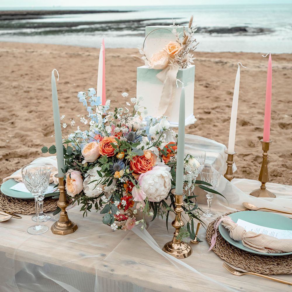 Pastel wedding inspiration by the sea with square two tier wedding cake, flowers and candles 