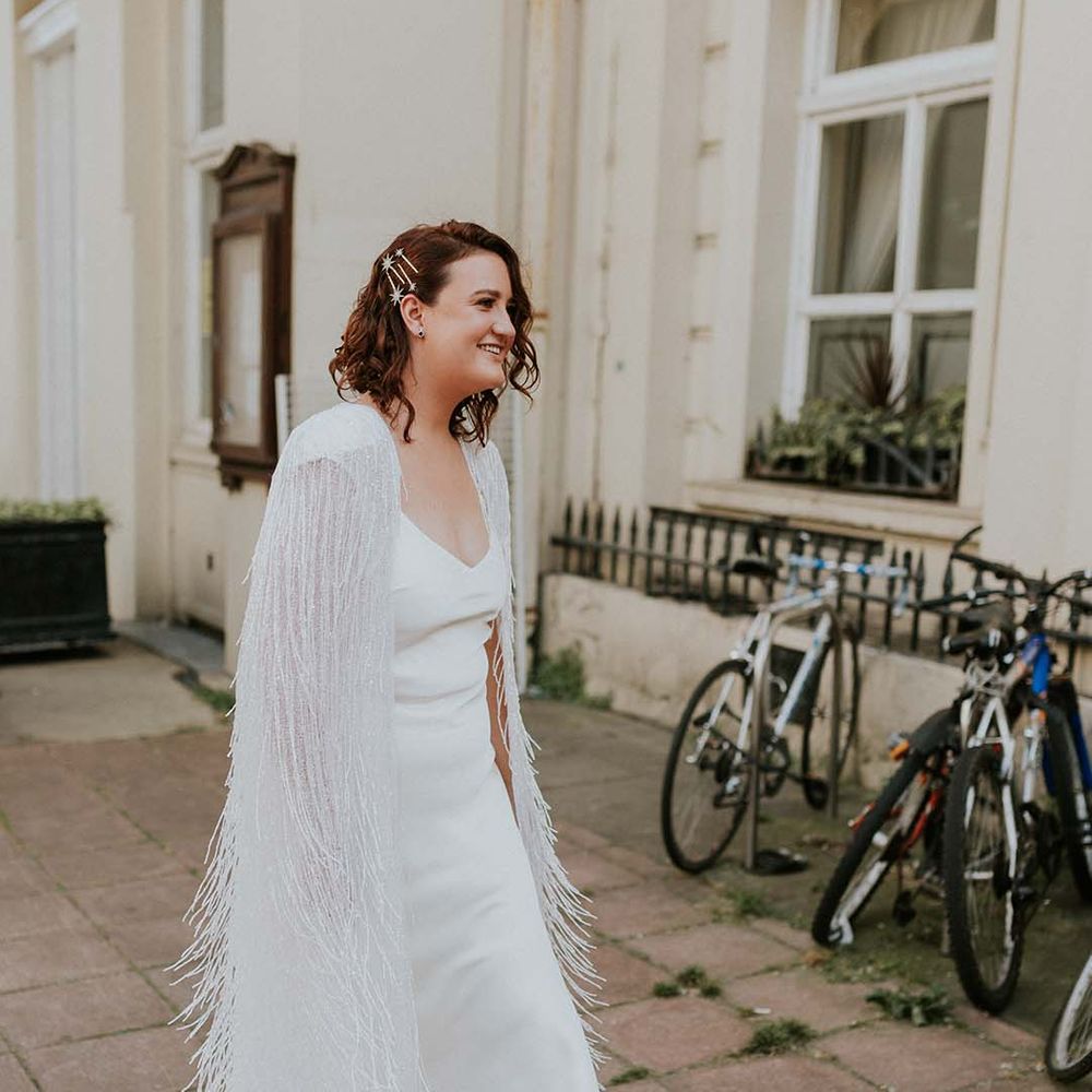 Bride walks to ceremony wearing Halfpenny London tassel cape