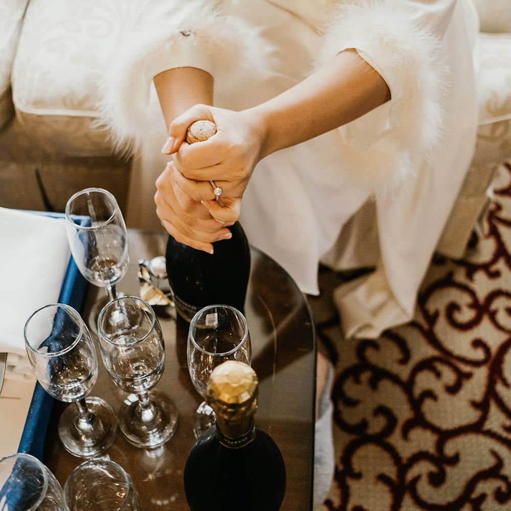 Feather sleeve robe for bride as she opens champagne