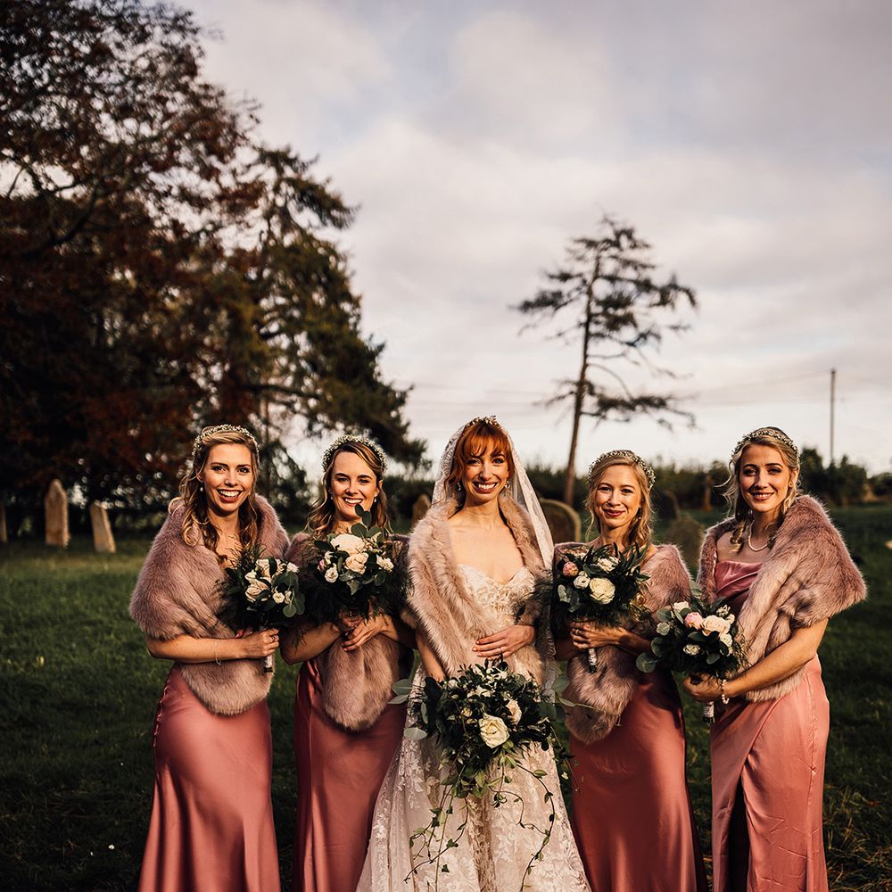Pink bridesmaid dresses with faux fur wraps at winter wedding