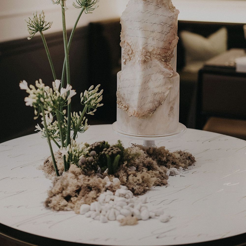 Tall white wedding cake with aged scrip decoration 