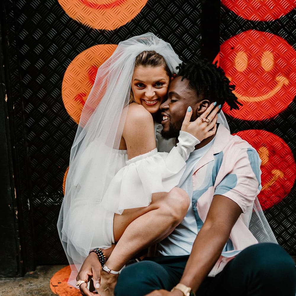 Fun urban elopement with bride in a short wedding dress and long veil and groom in a patterned shirt