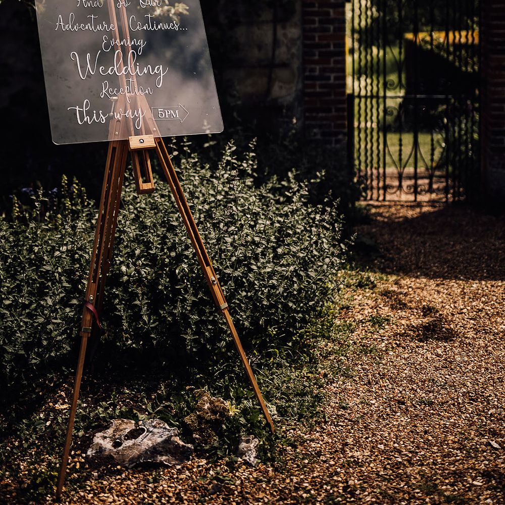 Clear wedding sign directing guests to the evening reception on easel 