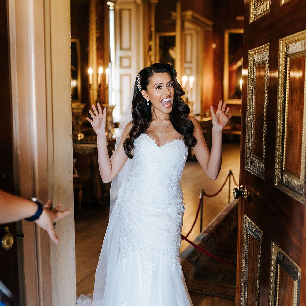 Indian bride wears her hair in loose curls complete with embellished hair accessory and lace sweetheart neckline wedding dress with mermaid train