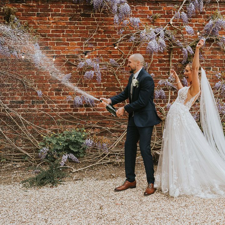 Groom sprays a bottle of champagne as he celebrates his wedding to the bride at Stanlake Park