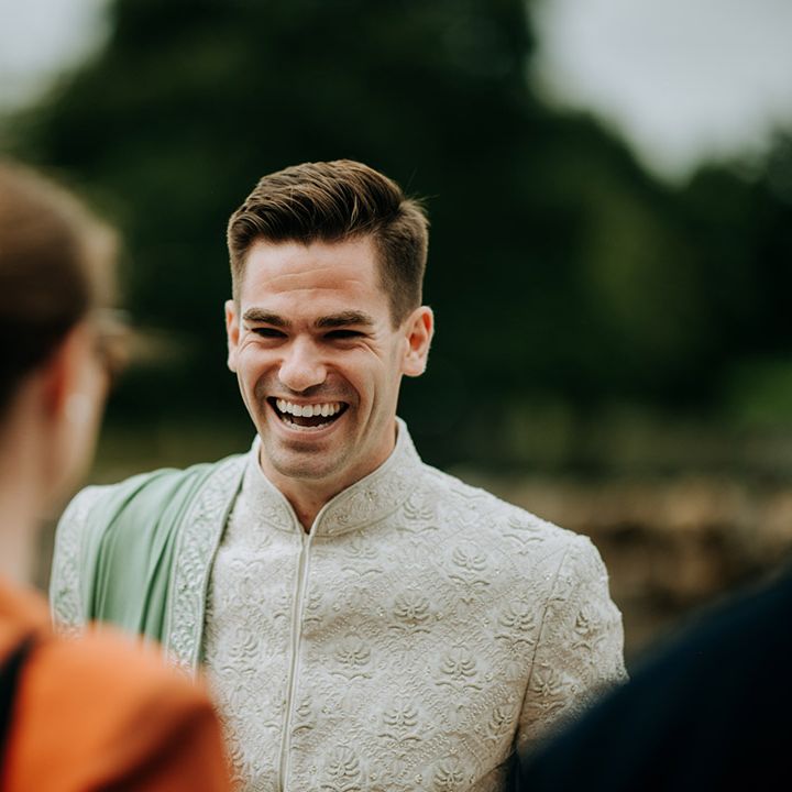 Groom wears embellished sherwani complete with sage green fabric across his shoulder