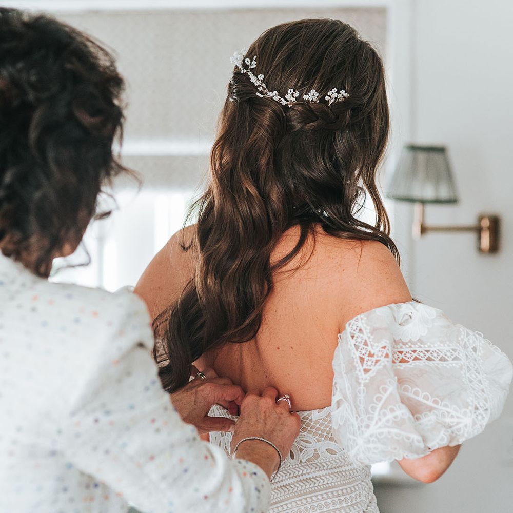 Bride with brown hair in a half up half down hairstyle with white flower accessory 