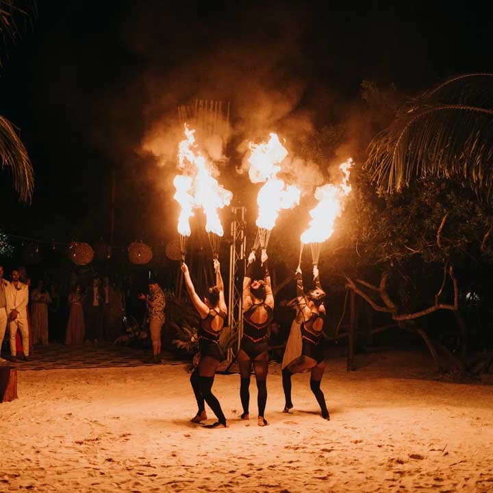 Grooms and wedding guests watching fire dancers at destination LGBTQIA+ wedding in Mexico 