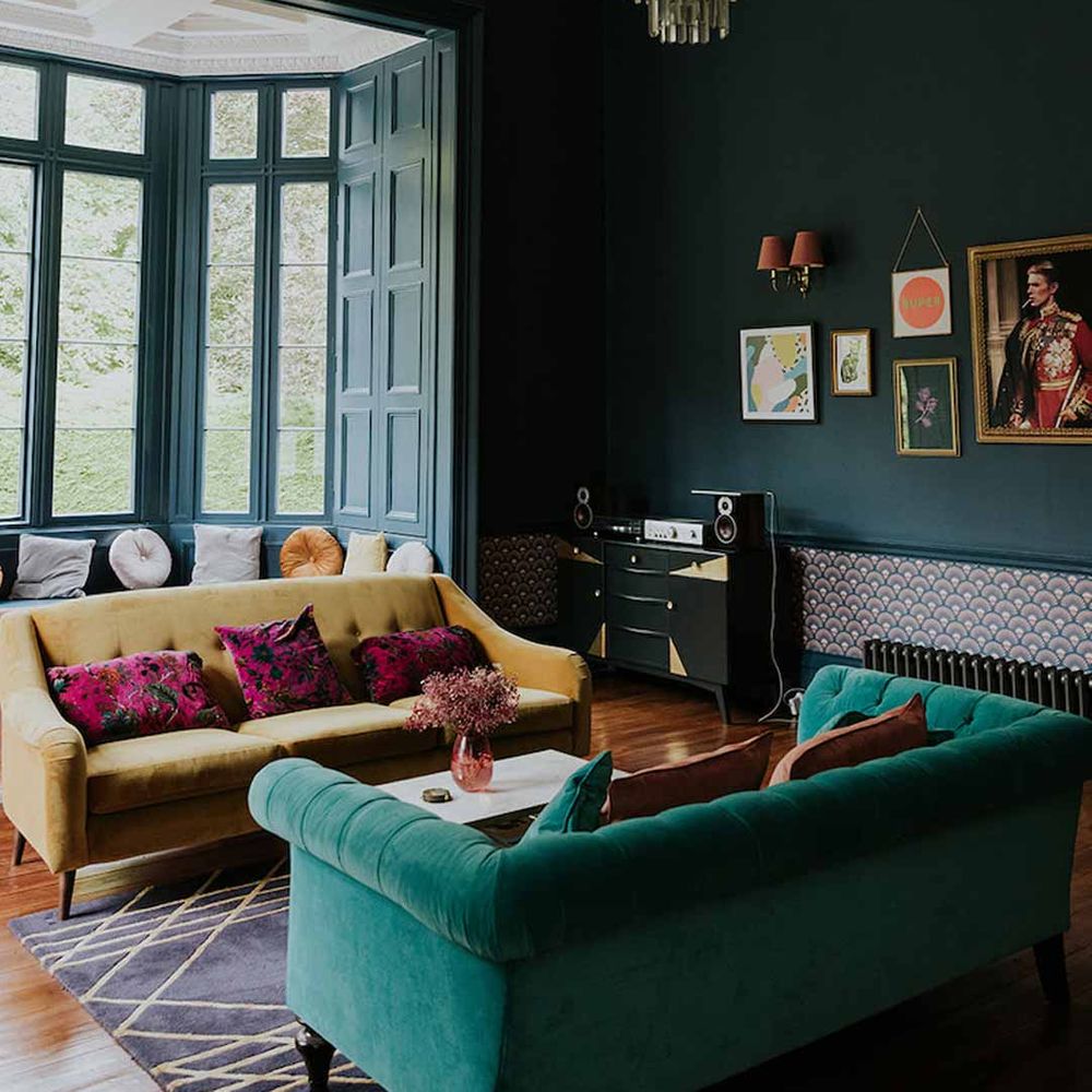 Netherbyres House wedding venue Scotland with deep teal and olive green velvet sofas, alternative crystal chandelier and bay windows overlooking manicured lawns