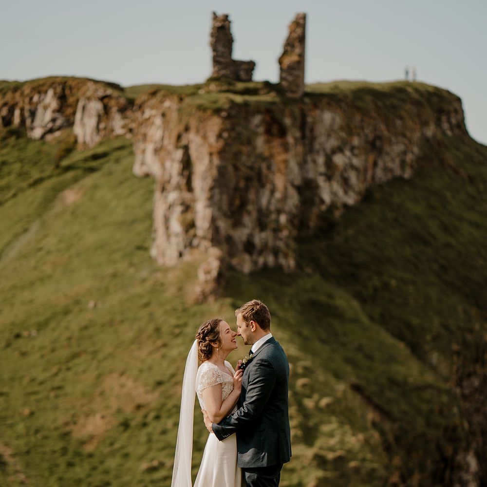 Dunluce Castle ruins wedding venue in Northern Ireland with bride and groom embracing 