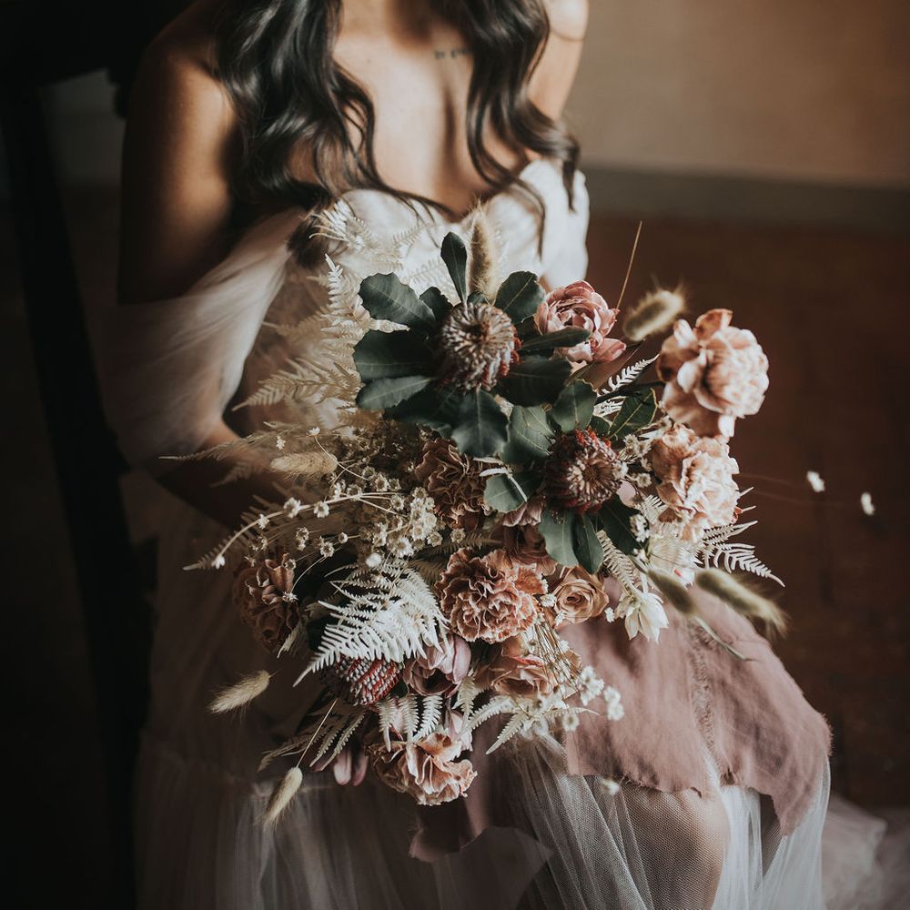 Bride with wavy hair and off the shoulder wedding dress holding her bridal bouquet 