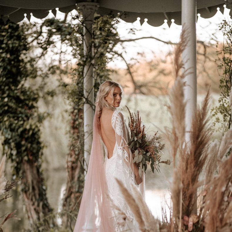 The Bride's blush pink veil trails over her lace boho dress