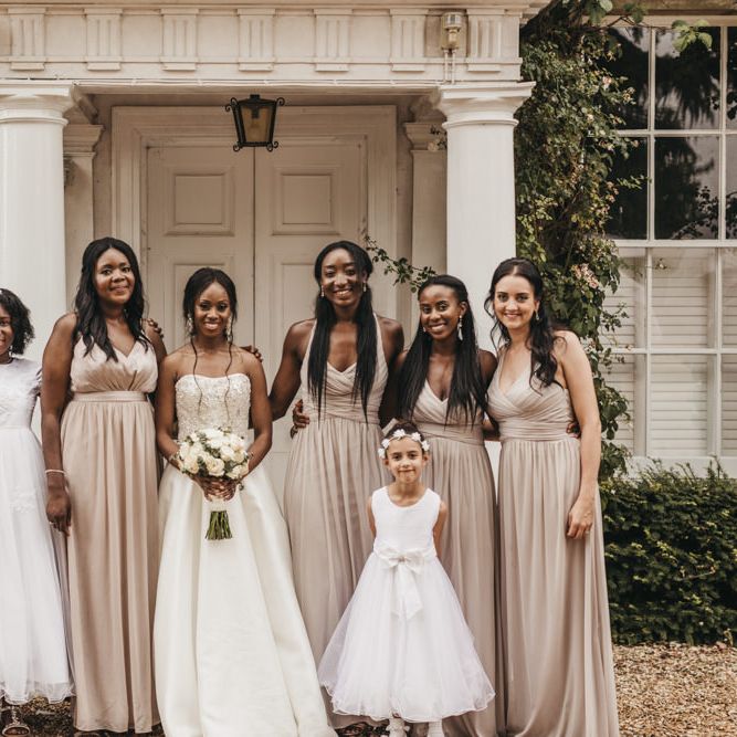 Bridal party portrait with Black bride in a Oleg Cassini wedding dress, Junior bridesmaid and flower girl in a white dresses, and Bridesmaids in dusky pink chiffon dresses