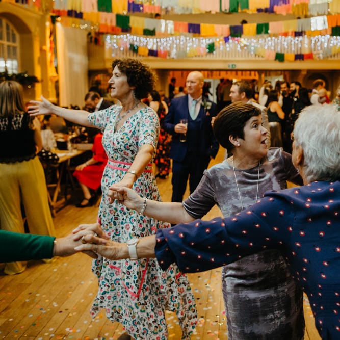 Wedding guests in floral dresses dancing at DIY wedding 