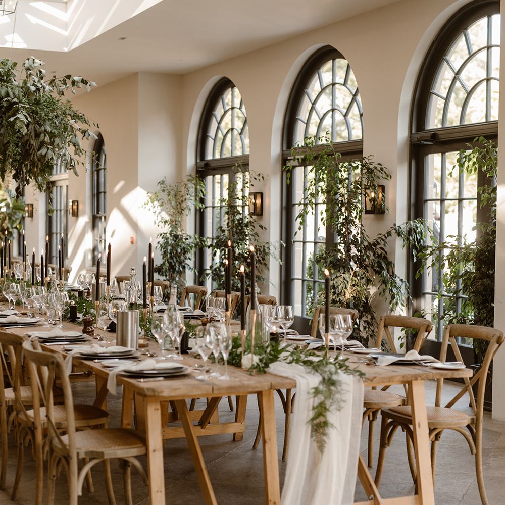 Wooden wedding table with rustic decor, wooden chairs, foliage cloud, greenery and black candles in the Fig House at Middleton Lodge