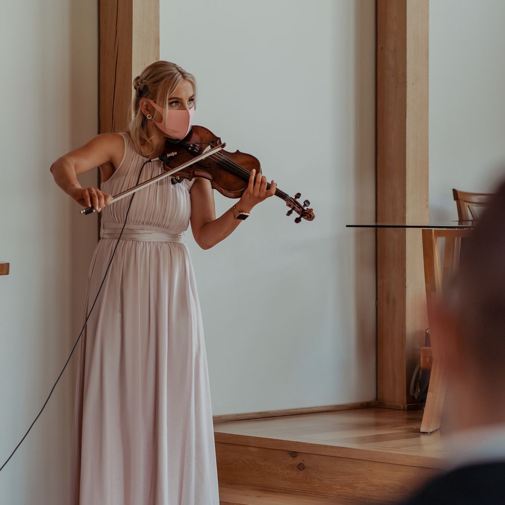 Violinist plays whilst wearing blush pink face covering at wedding ceremony
