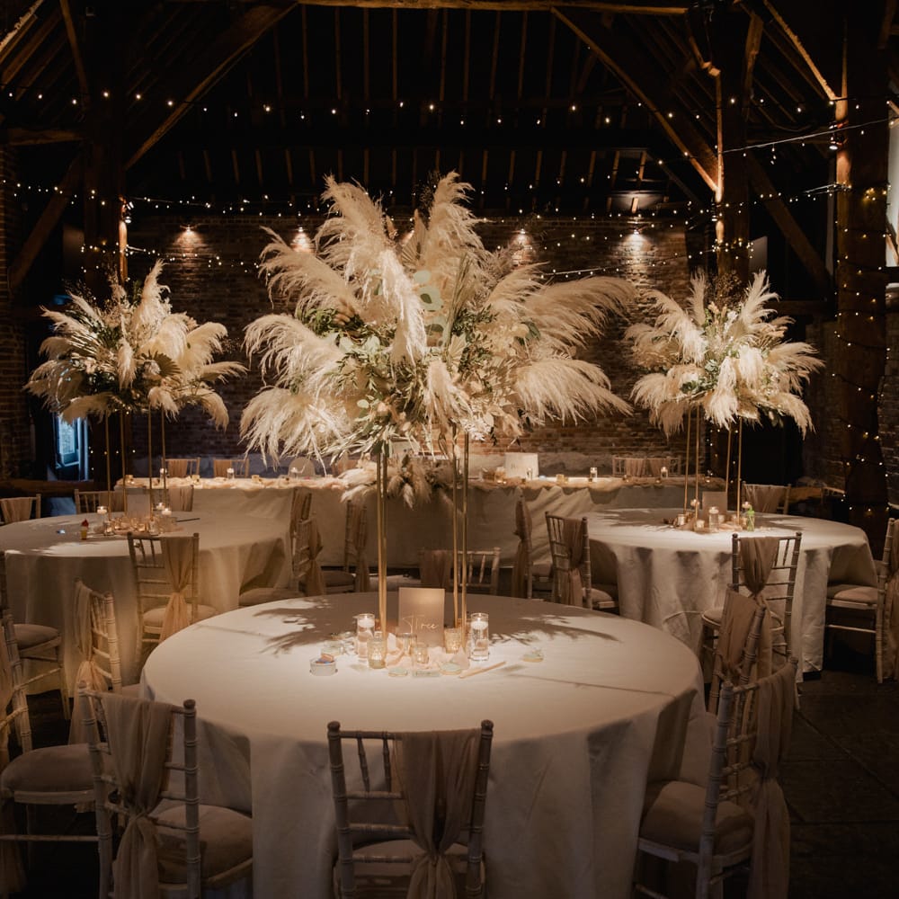 Cooling Castle Barn wedding reception with fairy lights and pampas grass centrepiece table decor 