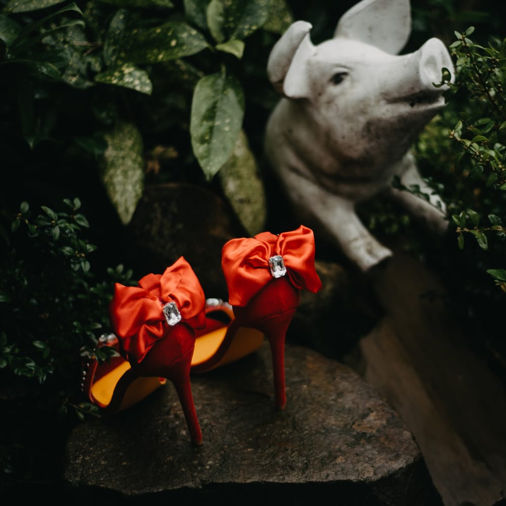 Red satin heeled sandals with bow at rustic wedding in Lancashire