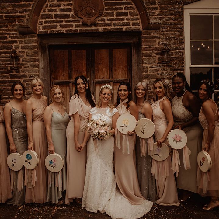 Bridal party portrait with bridesmaids in different dresses holding tambourines instead of bouquets 