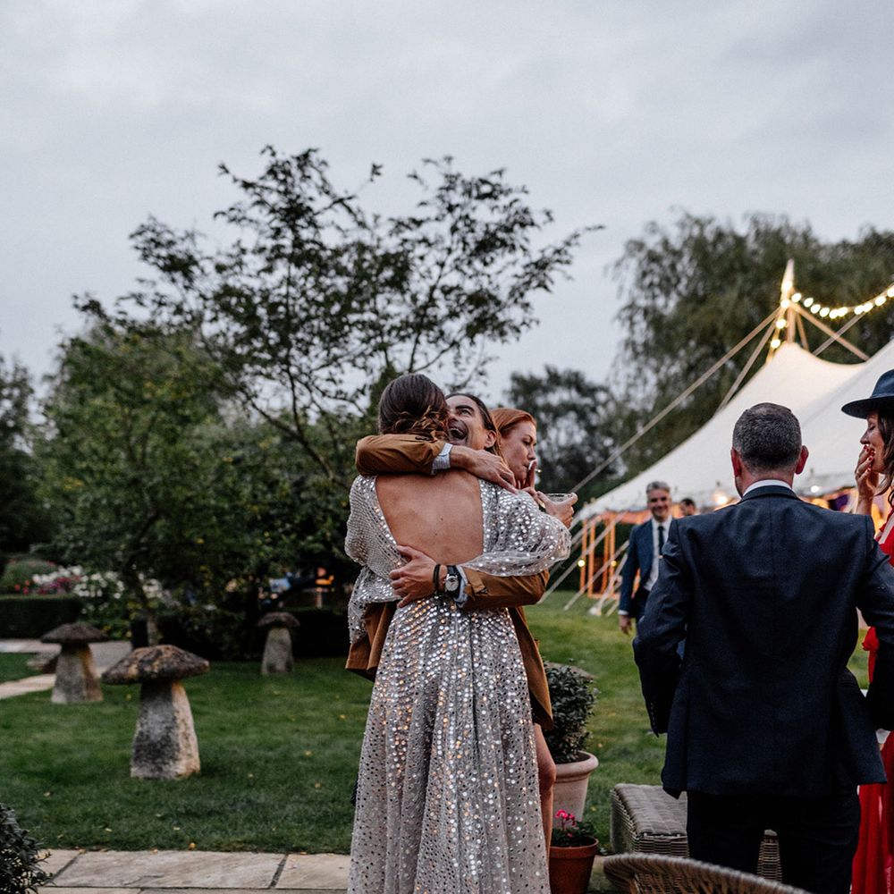 Wedding guest embracing the bride in a low back silver sequin wedding dress
