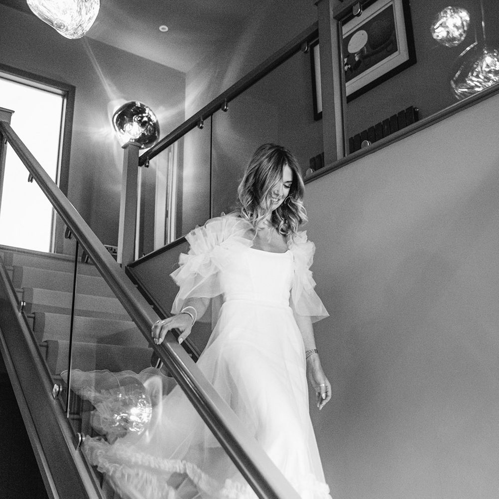 Bride makes her way down the stairs in Halfpenny London wedding dress
