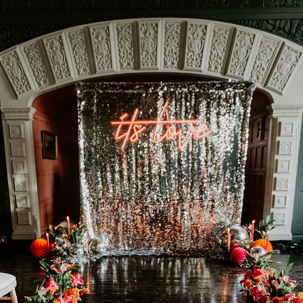Retro Aisle wedding decor with silver sequin curtain, neon sign, red tulip bouquet and aisle wedding flowers 