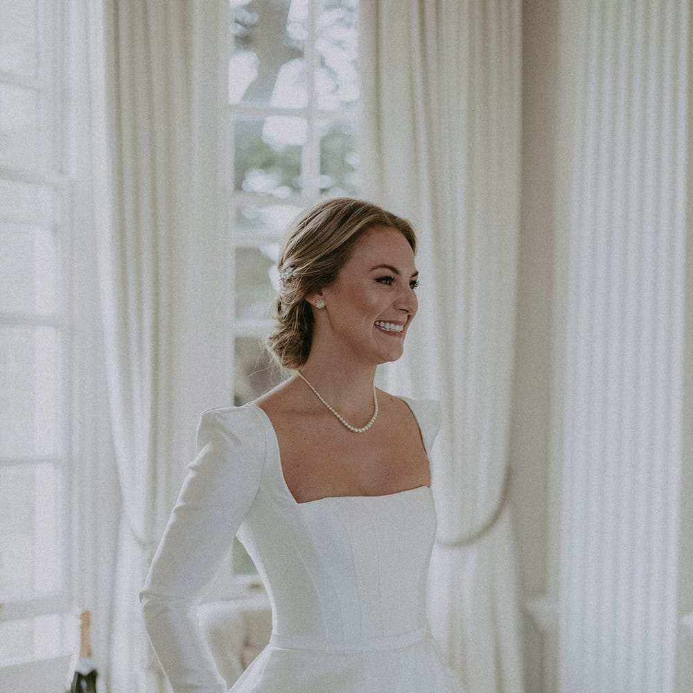 Bride in square neck, full skirt long wedding dress and pearl necklace