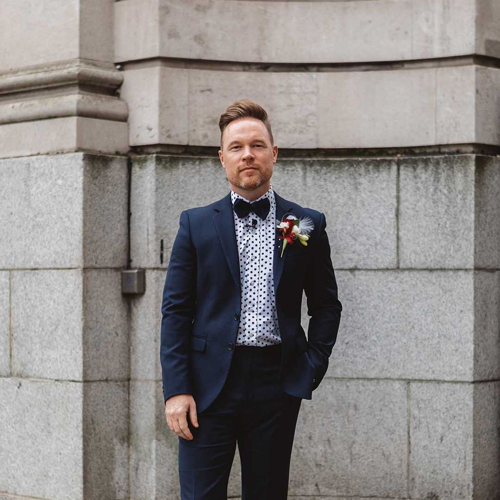 Grooms wears deep blue suit complete with bow tie and polka dot shirt