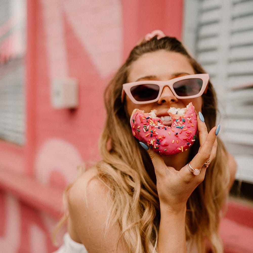Groom in pink retro sunglasses eating a sprinkle doughnut 