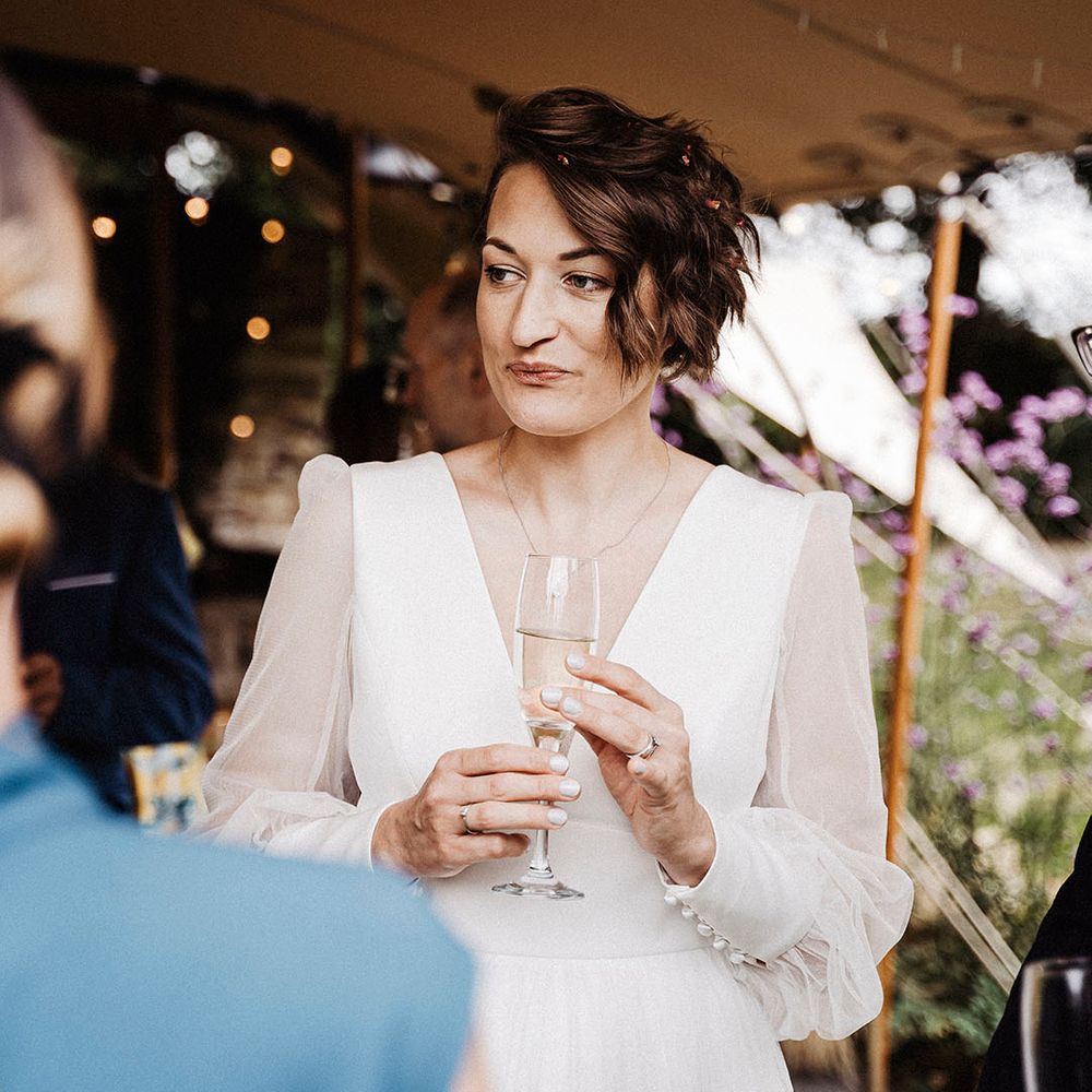 Bride with short white wedding nails wearing sheer long sleeved Sassi Holford wedding dress
