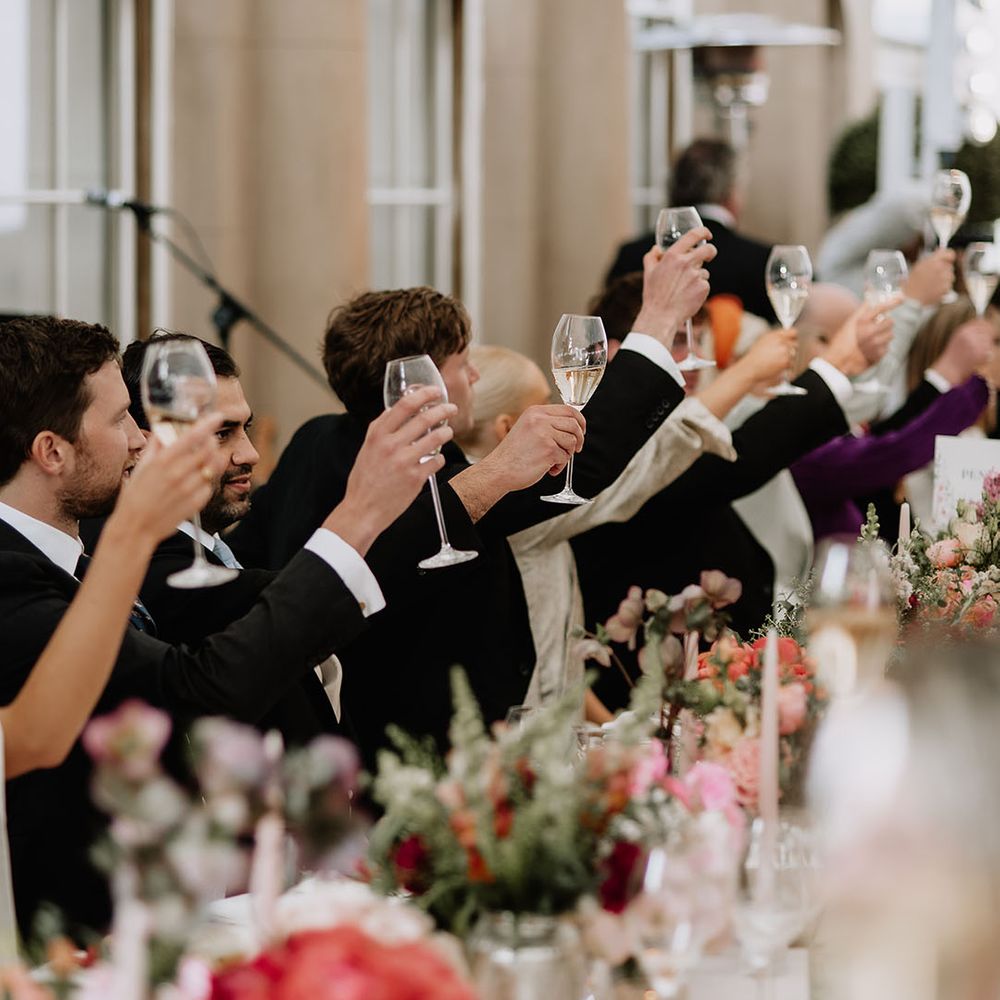 Wedding guests raise their glasses of wine in a toast for the bride and groom 