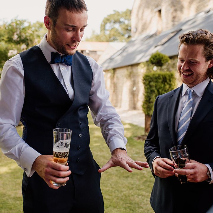 Groom shows off his new wedding band to the groomsmen as he drinks a beer 