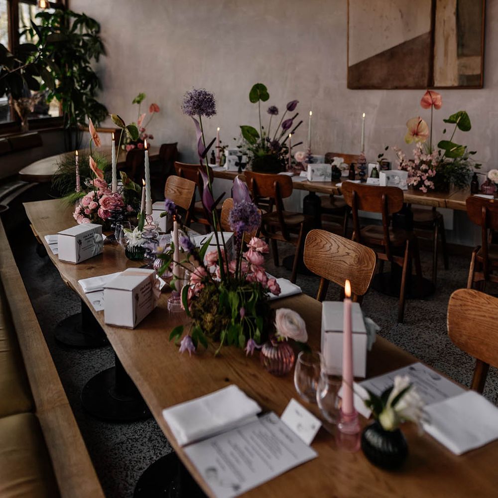 wedding table decor with modern flower centrepieces and boxed wedding favours on wooden tables 