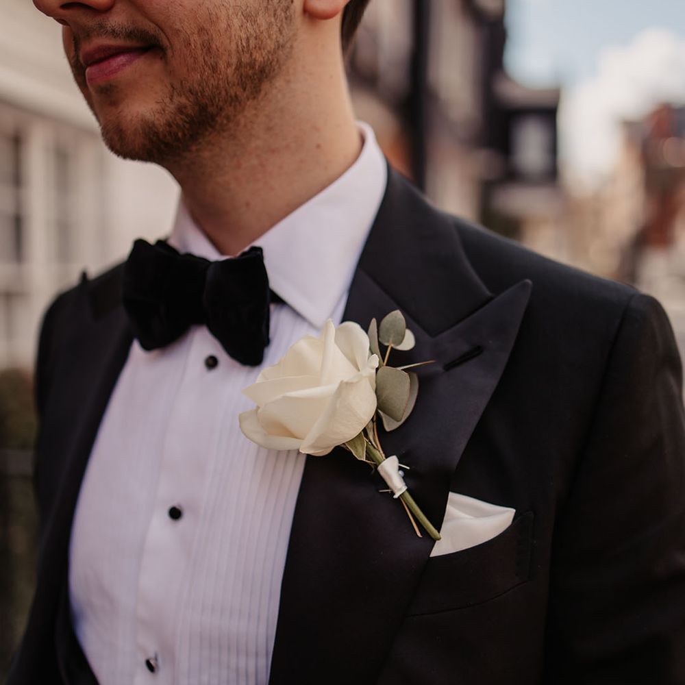 Groom in black tie with white rose buttonhole 
