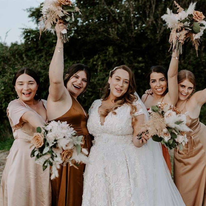 Bride in homemade short sleeve lace wedding dress and bridesmaids in DIY orange and red satin bridesmaid dresses