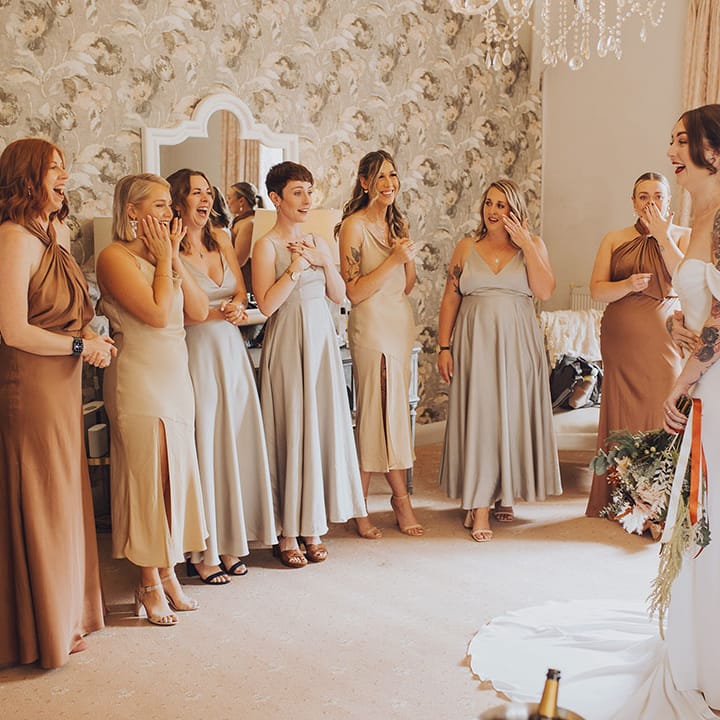 Bridesmaids in mismatched bridesmaid dresses and different colouring see their bride for the first time 