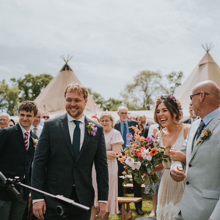 Bride laughs wearing colourful floral crown for outdoor wedding ceremony