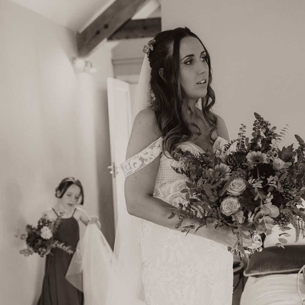 Bride in boho fitted wedding dress ready for the bouncy castle wedding with her daughter in burgundy dress 