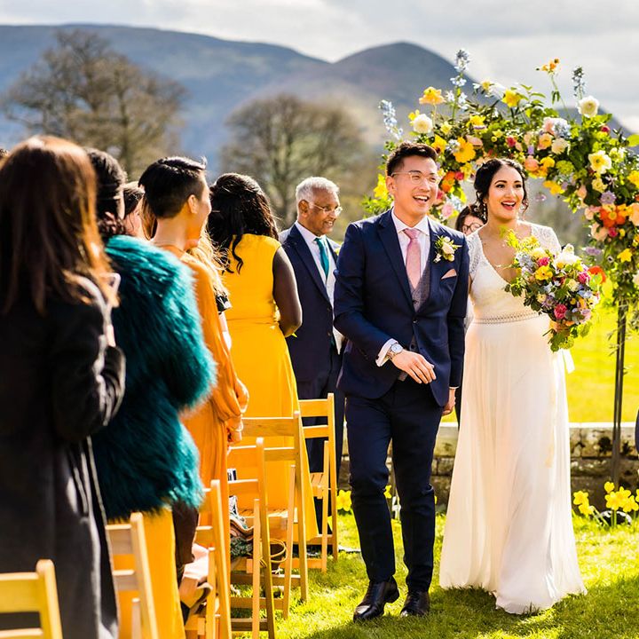Bride holds colourful floral bouquet during outdoor wedding ceremony at Plas Dinam wedding venue 