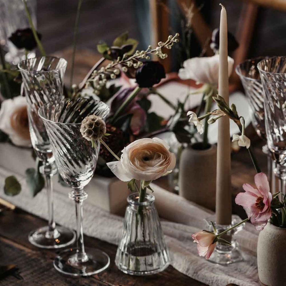 Modern rustic luxe wedding tablescape with white cloth table runner, delicate glasses and tapered candles 
