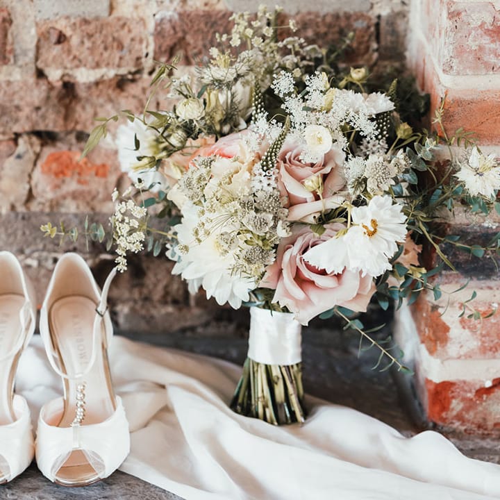 Rainbow wedding shoes with pretty bow detail with the bride's pink and white bouquet with roses and cosmos 