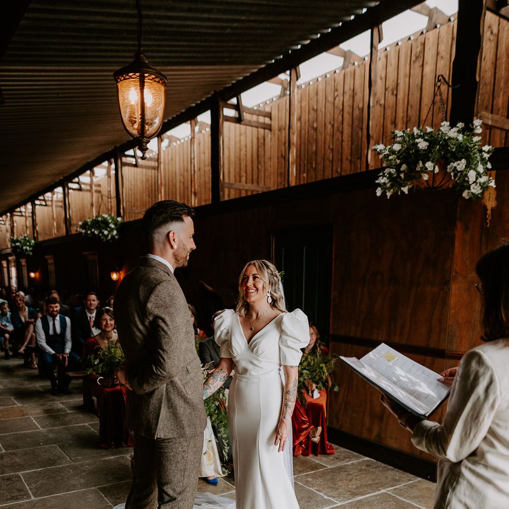 Bride wearing a fitted wedding dress with short puff sleeves standing with the groom at the altar 