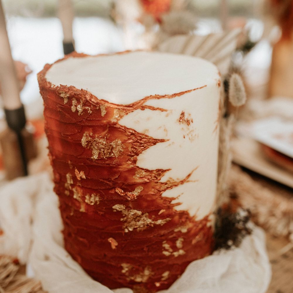 White and burnt orange wedding cake with gold leaf decoration 