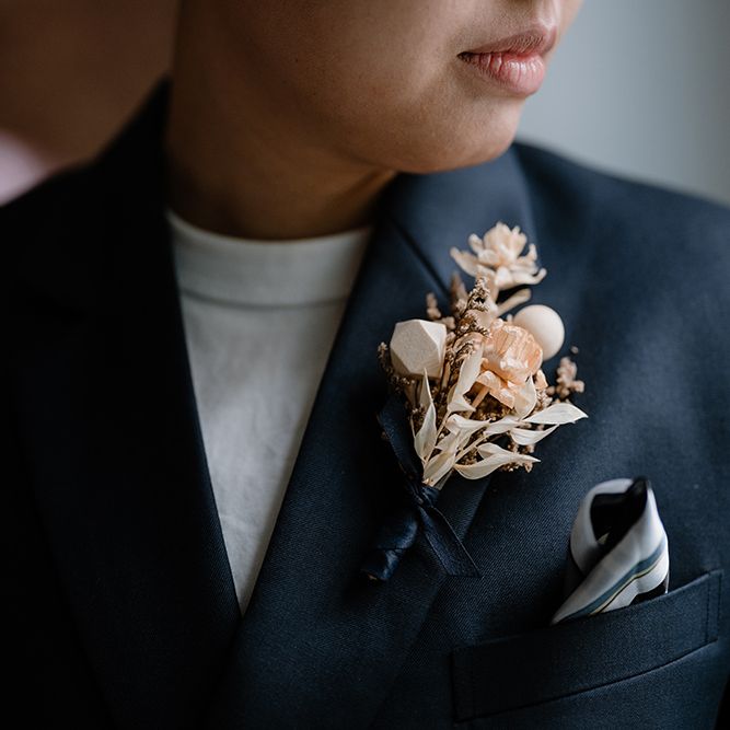 Asian bride in a navy wedding suit with neutral buttonhole