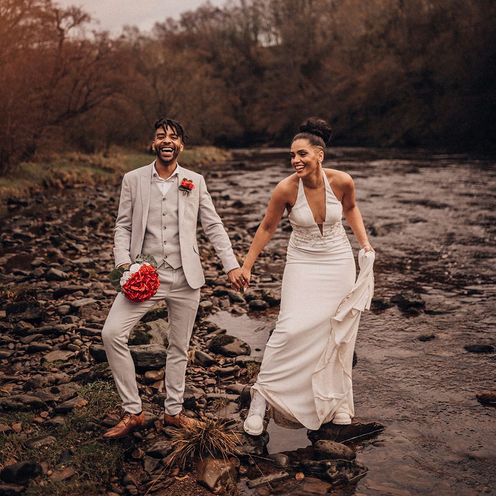 Bride & groom walk together outdoors as they hold hands and bride wears wedding Dr Martens