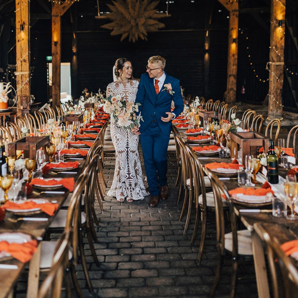 Boho Bride & Groom in Barn wedding surrounded by pampas installations, autumnal coloured dinner table settings & fairylights at Elmley Nature Reserve